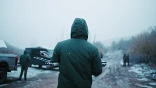 Siembra de nubes con drones: un técnico de Rainmaker, de espaldas, lleva un dron en las manos bajo la nieve