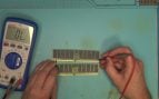 Los dos módulos de memoria RAM DDR5 de servidor de 128 GB y 256 GB sobre la mesa de trabajo mientras el técnico de northwestrepair los mide con un polímetro