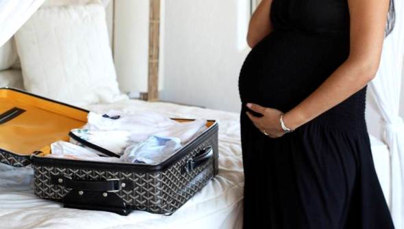 Pregnant woman packing suitcase