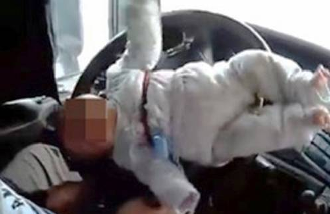 Un padre conduce teniendo atado al volante a su bebé