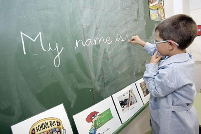 Niño escribe inglés en la pizarra del colegio
