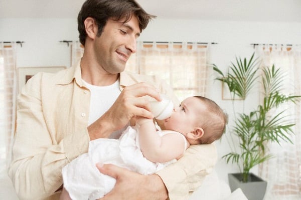 Father feeding infant --- Image by © Maria Teijeiro/cultura/Corbis