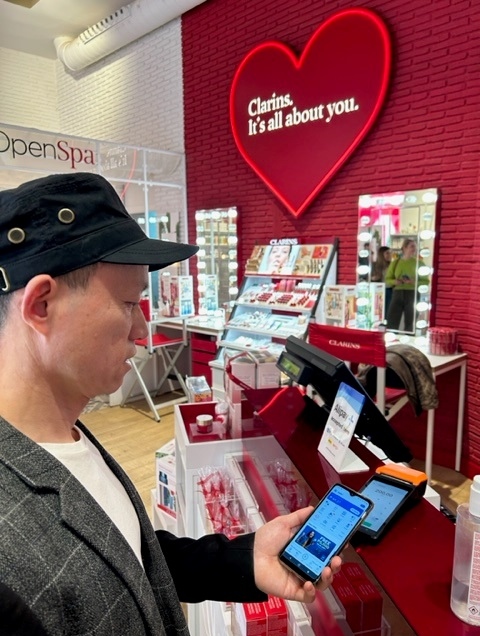 Un hombre pagando por Alipay en Clarins
