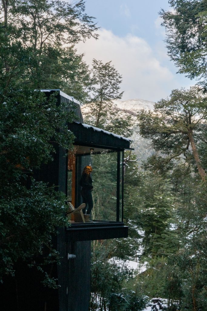 Una mujer mira por la ventana de una mini casa en la Patagonia Argentina