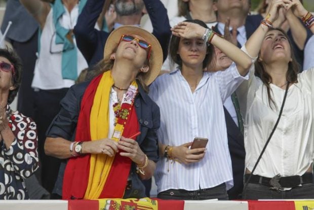 La infanta Elena acudía al desfile con sombrero y una bandera de España al cuello, acompañada de su hija Victoria Federica / Gtres