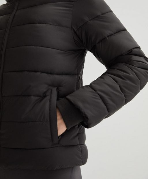 Modelo con chaqueta calefactable en color negro. / Oysho