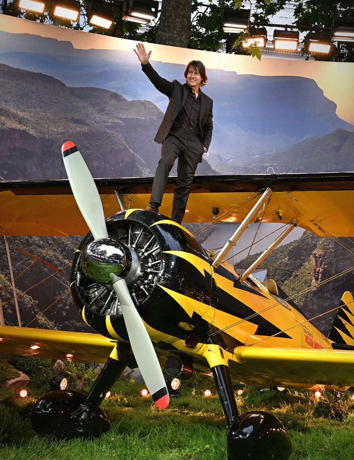 Tom Cruise aparece de pie sobre el ala de un avi&oacute;n biplano amarillo y negro. (Redes Sociales)