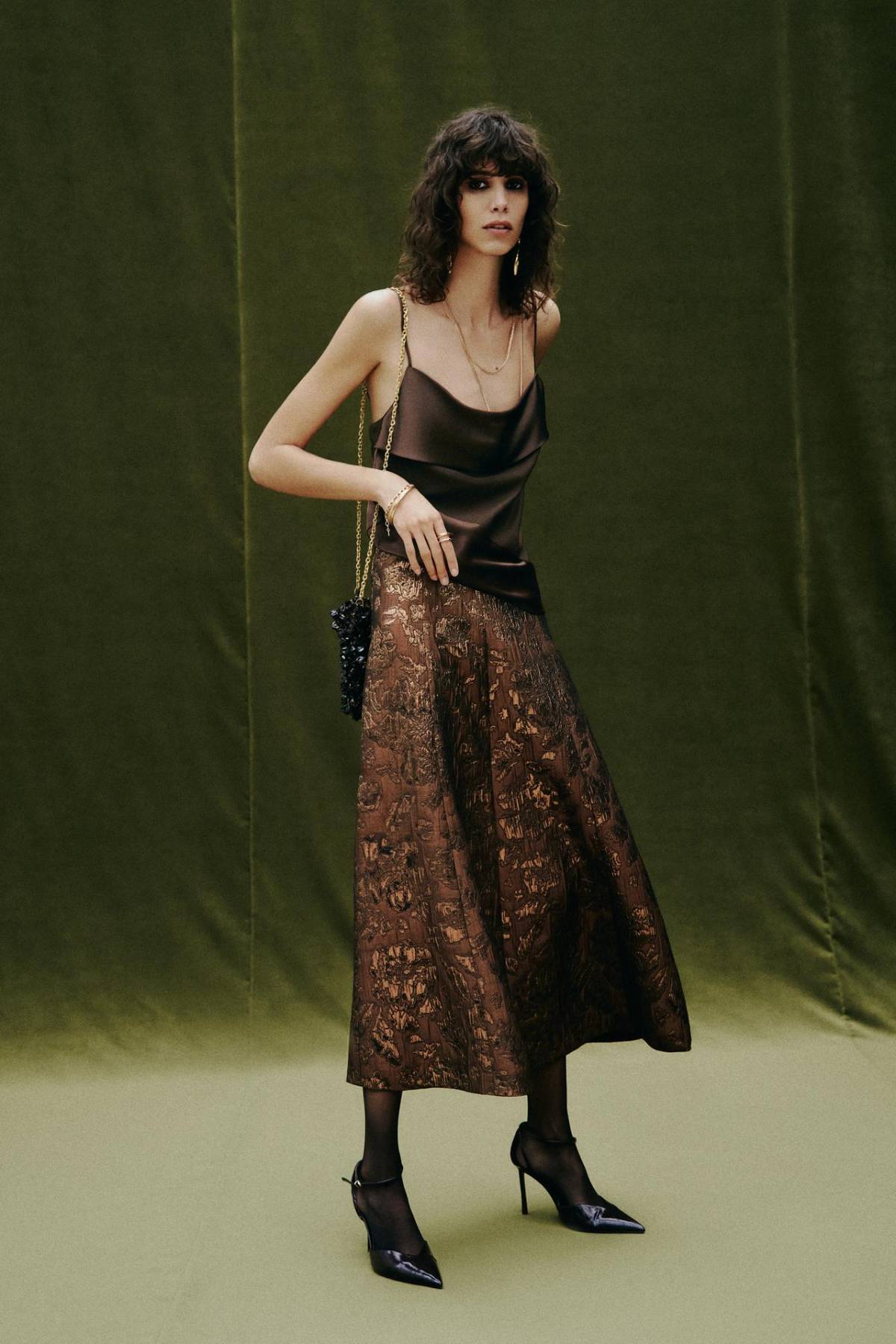 Falda capa de jacquard combinada con top lencero satinado y bolso de abalorios.