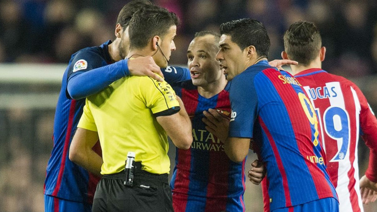 Los jugadores del Barcelona rodean a un árbitro durante un duelo con el Atlético. (AFP)