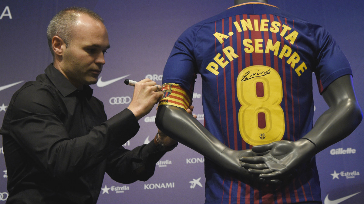 Iniesta firma en la camiseta conmemorativa de su renovación. (AFP)