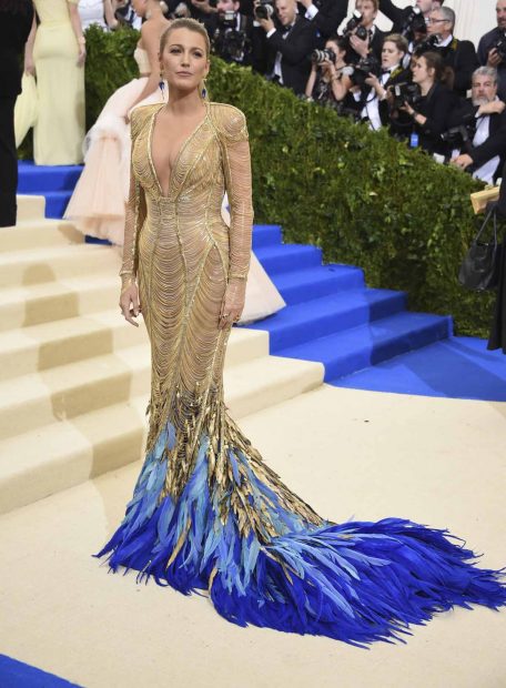 Blake Lively con un espectacular vestido de pliegues dorados y con detalles de plumas azul eléctrico en la parte de la cola. Diseño de Versace que lució en la Gala MET 2017/Gtres