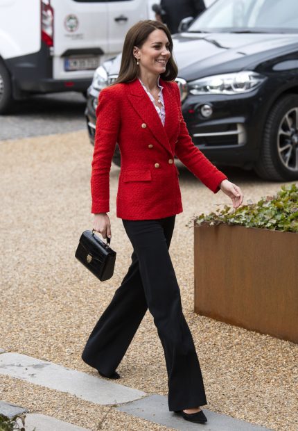 Kate Middleton en un acto público con un 'look' compuesto por una blazer roja y pantalón negro./Gtres