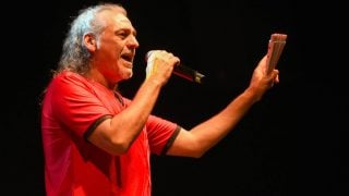 Dioni aparece en pleno escenario, con una camiseta roja, micrófono en mano y un abanico blanco. (Gtres)