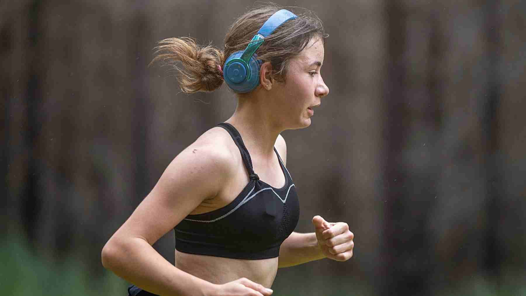 Adolescent distance runner training outdoors with headphones, illustrating improved running economy through power training