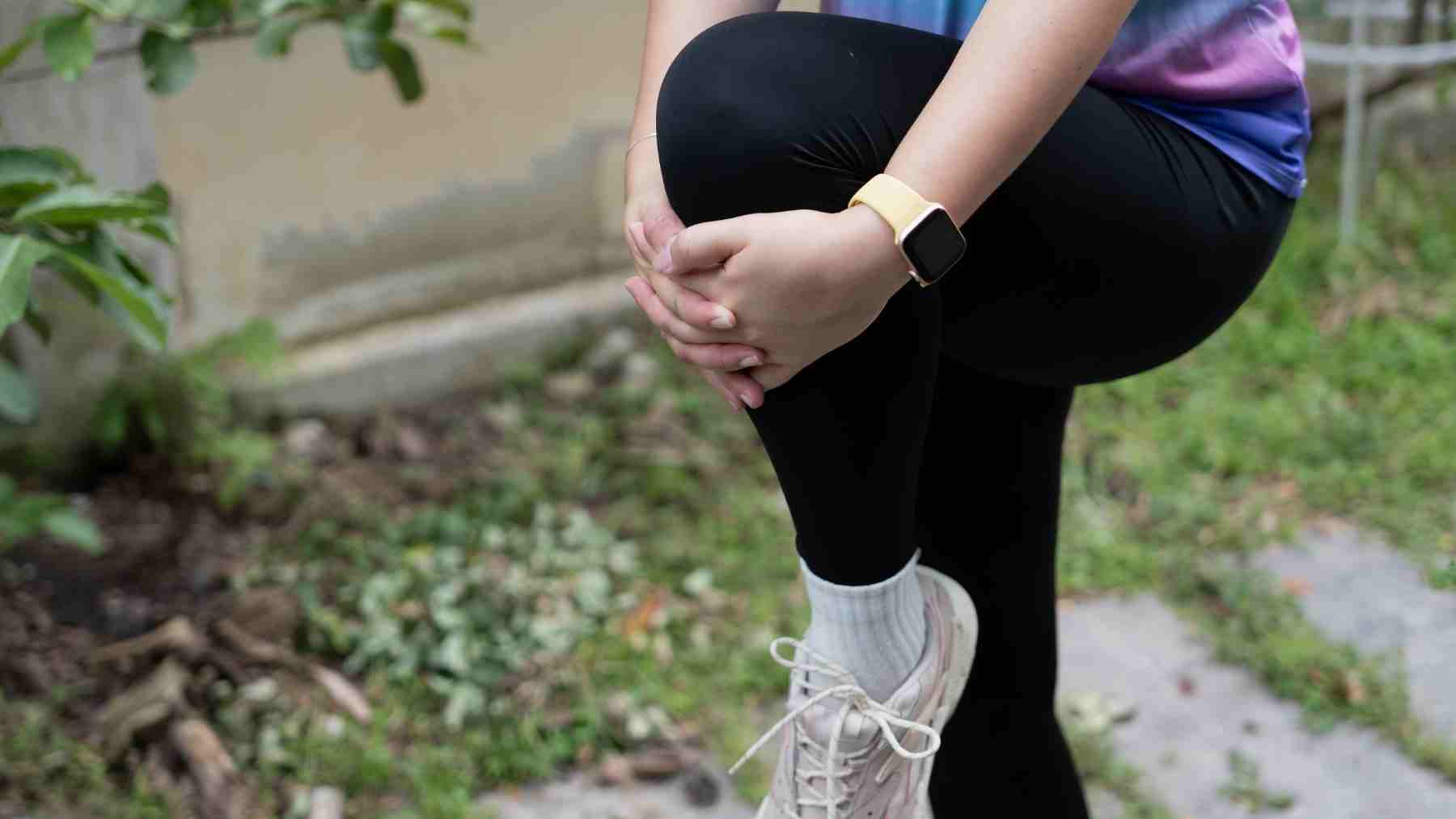 Runner stretching knee during warmup before a run, highlighting the importance of mental and physical preparation