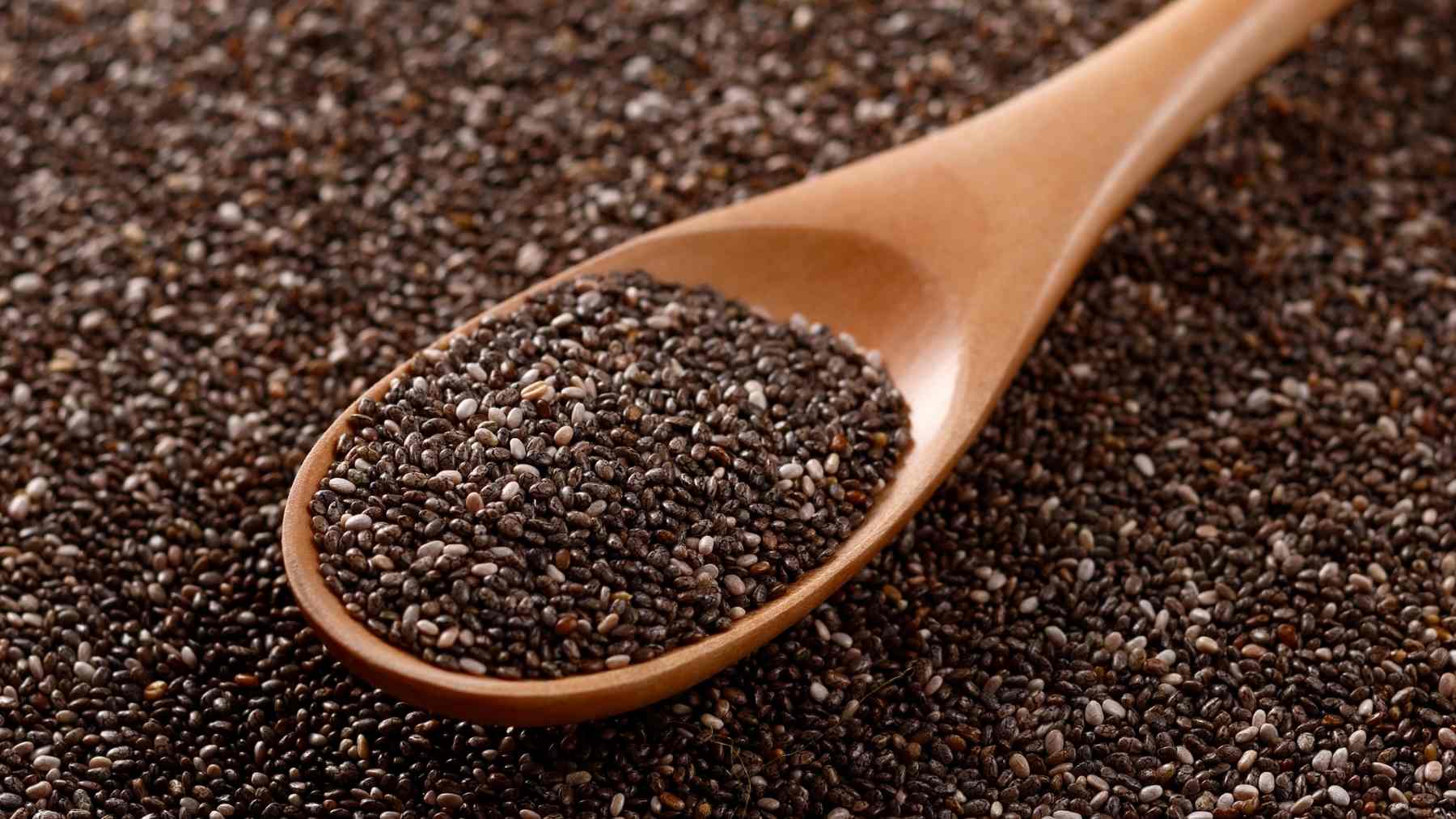 Chia seeds in a wooden spoon showing the tiny dry seeds that can cause bloating if eaten without soaking