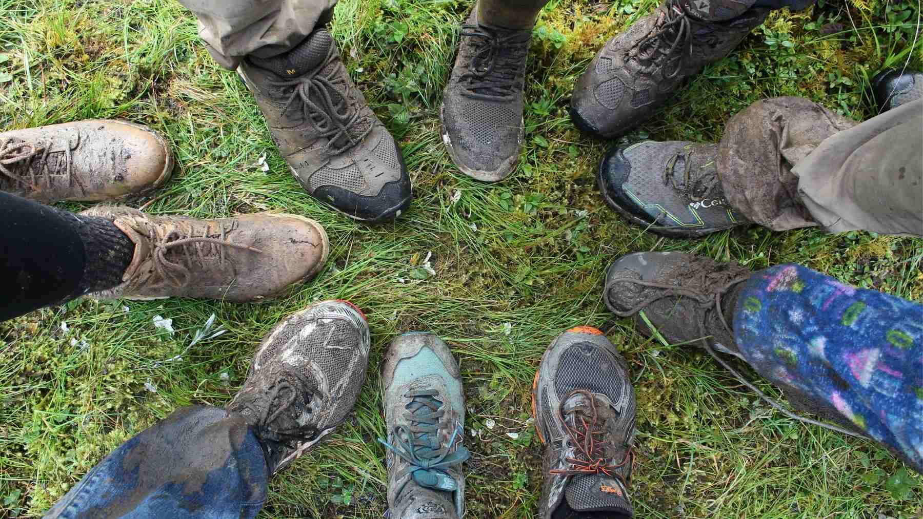 Group of people standing in a circle wearing muddy shoes after a walk outdoors, highlighting everyday physical activity
