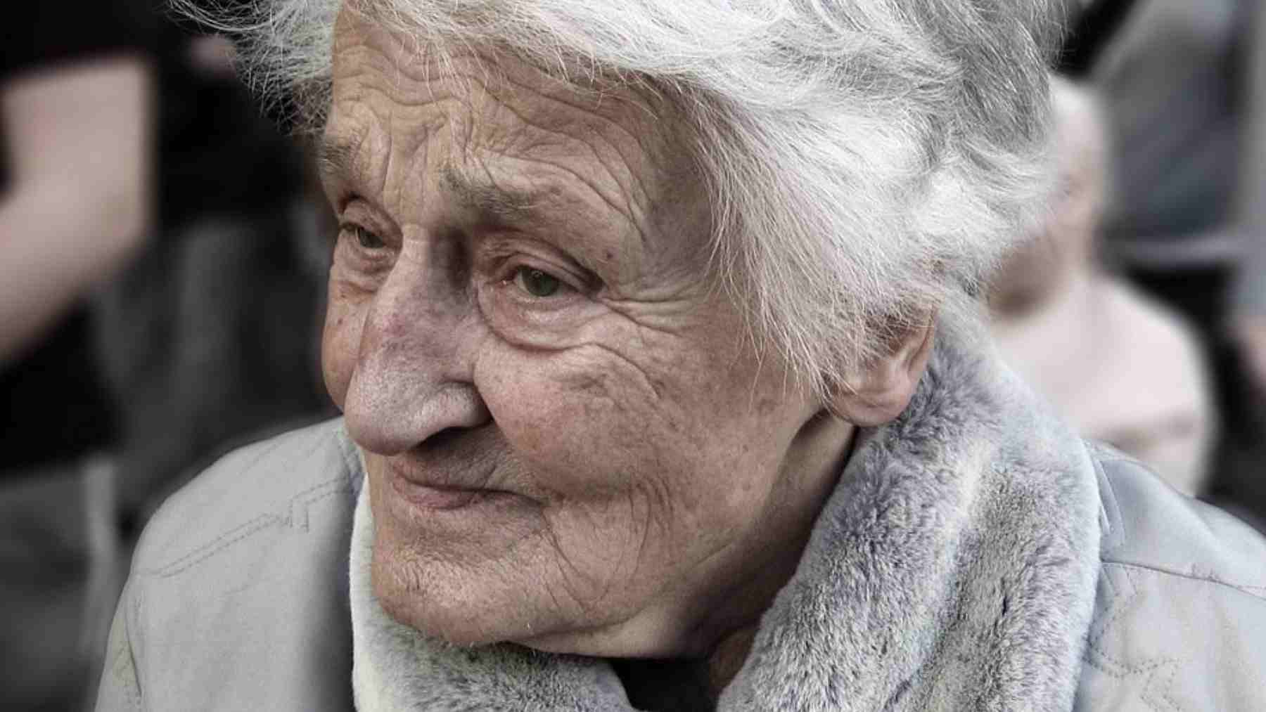 Elderly woman looks lonely in a crowd, illustrating existential isolation and feeling unseen around others.