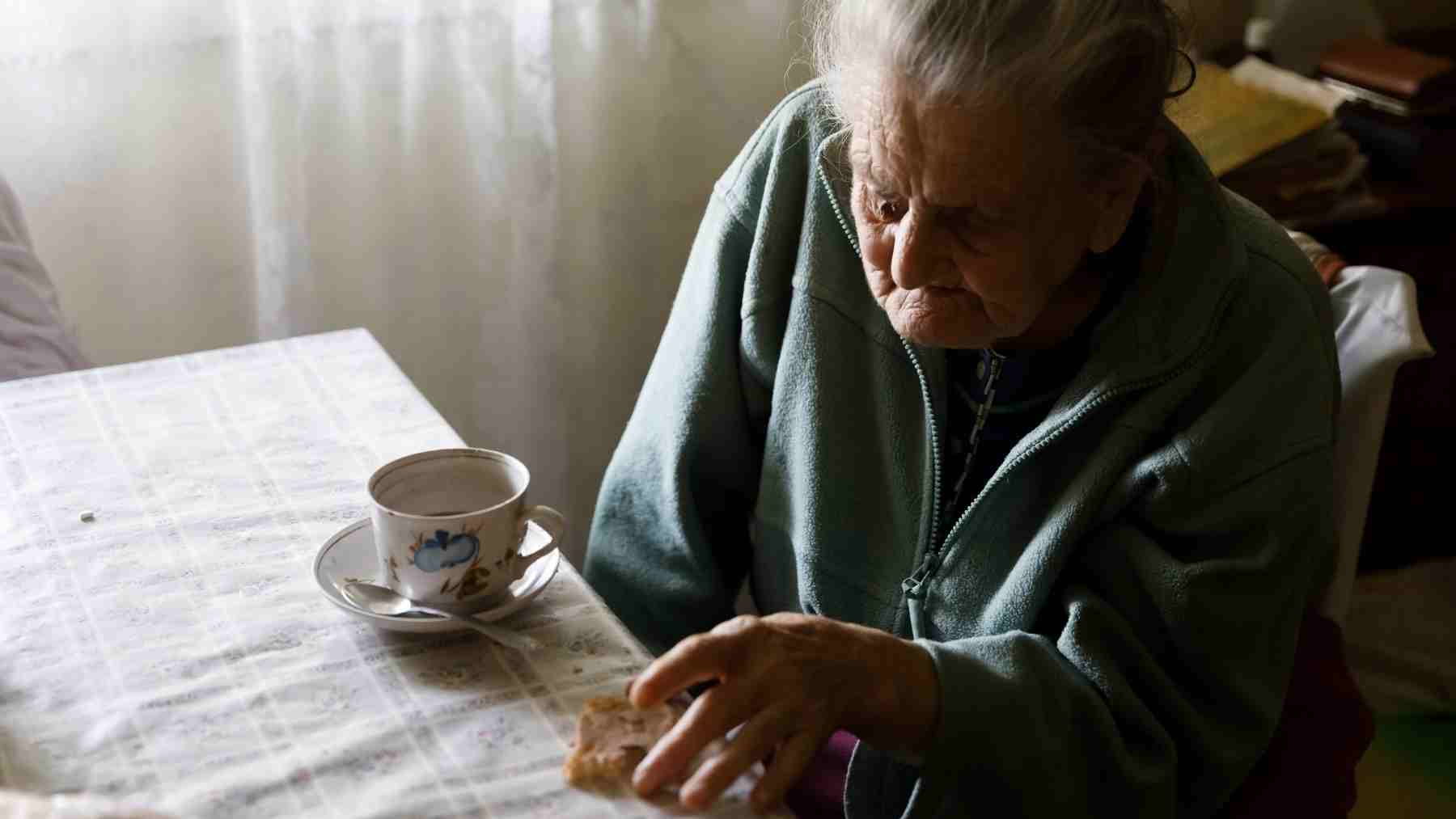 Older woman sitting alone at a table, reflecting loneliness and its impact on memory in aging adults