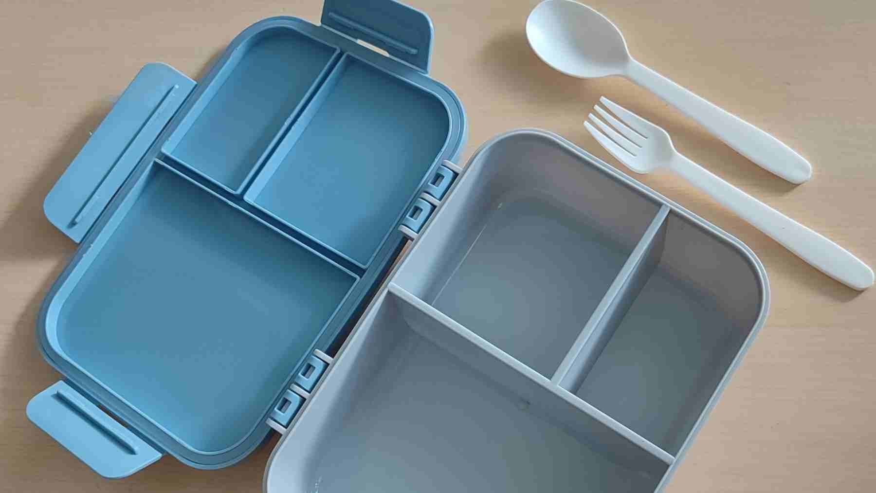 Empty divided lunchbox container with compartments and utensils ready for healthy meal prep