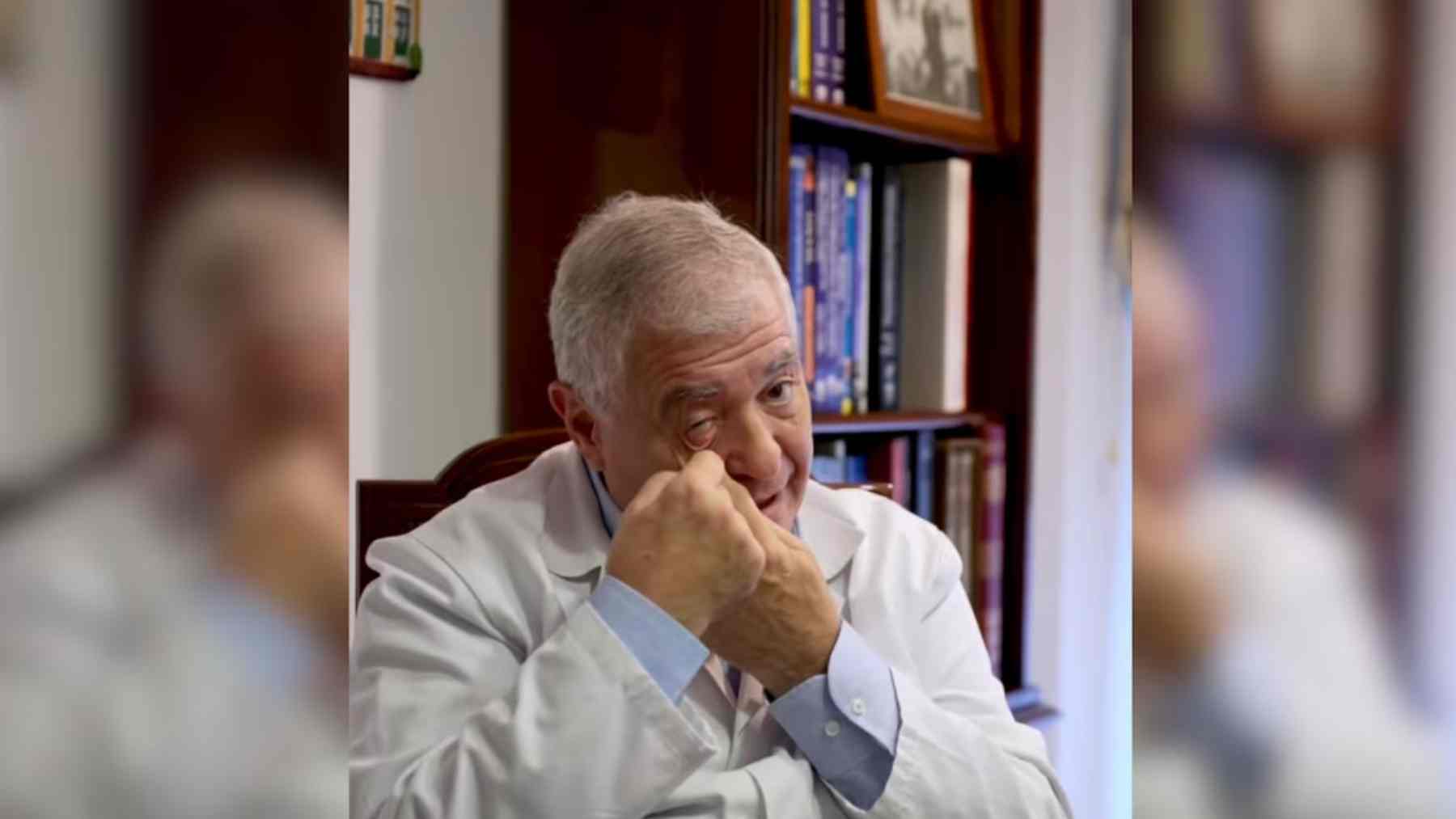 Miguel Saldaña in a white coat points to his lower eyelid while explaining surgeries that can avoid visible scars