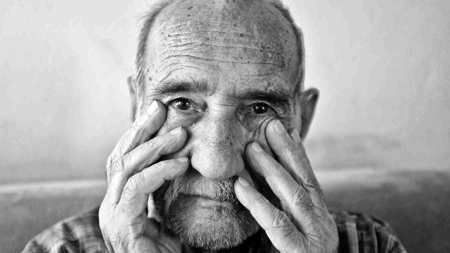 Older man touching his face, reflecting the psychology of aging, emotional selectivity, and selective attention.