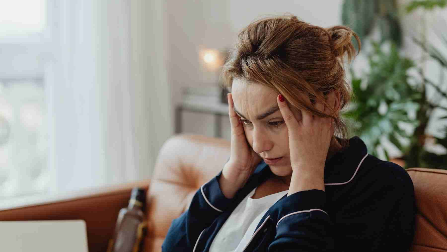 Woman holding her head in stress reflecting emotional isolation and fear of closeness linked to avoidant attachment