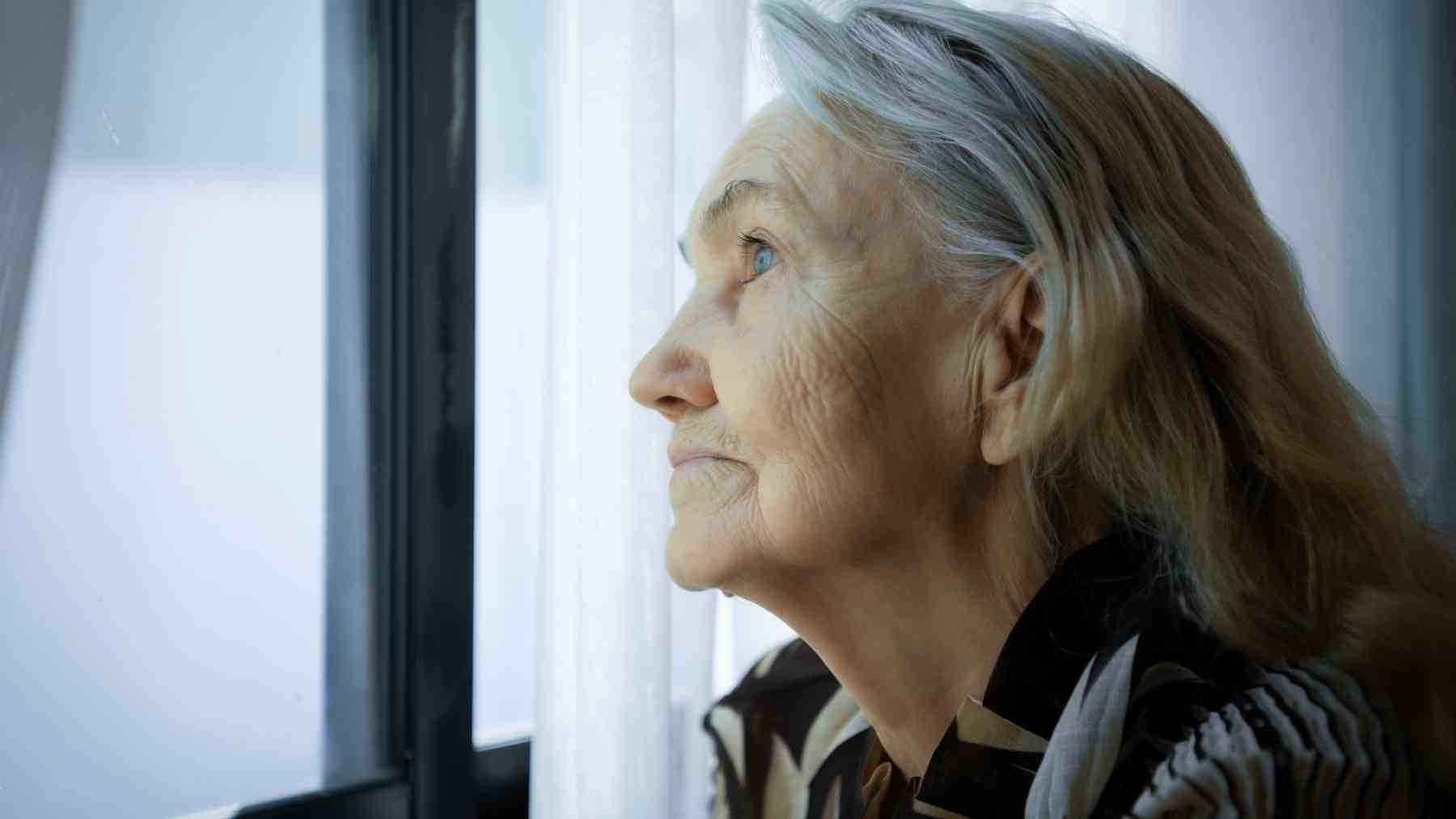 Older woman looking out a window reflecting on failure, social comparison, and hidden setbacks