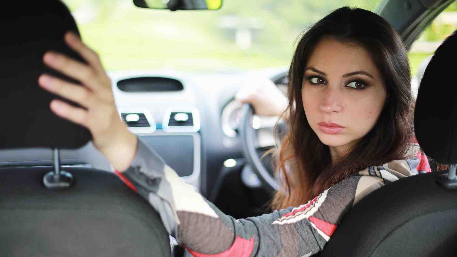 Woman looking over her shoulder while backing into a parking space, illustrating research on reverse parking and safety