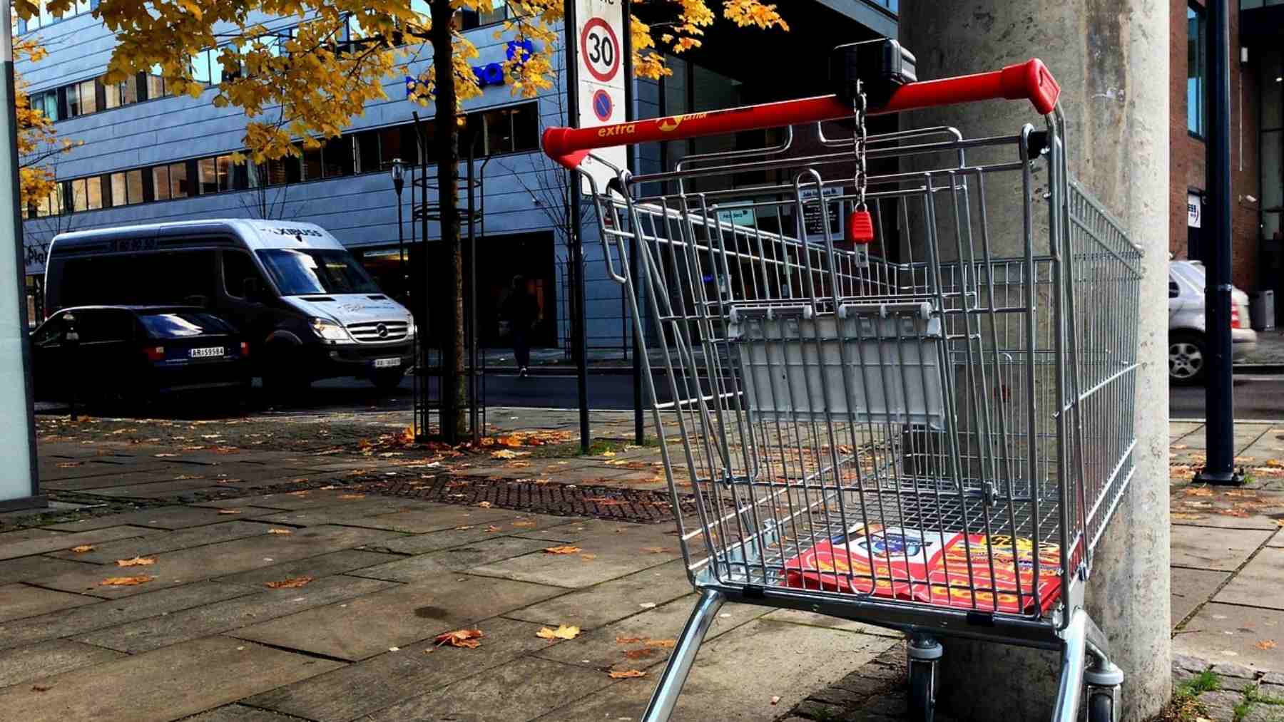 Shopping cart parked neatly beside a sidewalk barrier on a city street