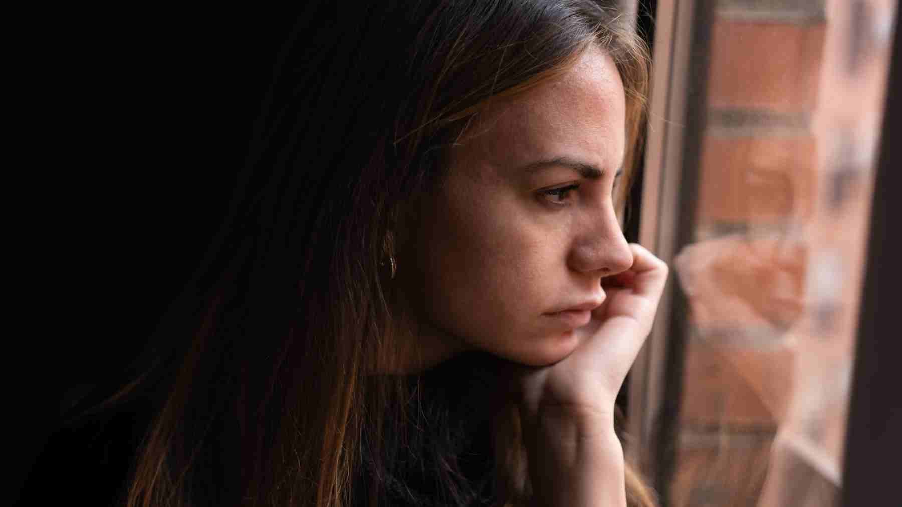Teen girl looking out a window appearing thoughtful, representing adolescent mental health and friendship support