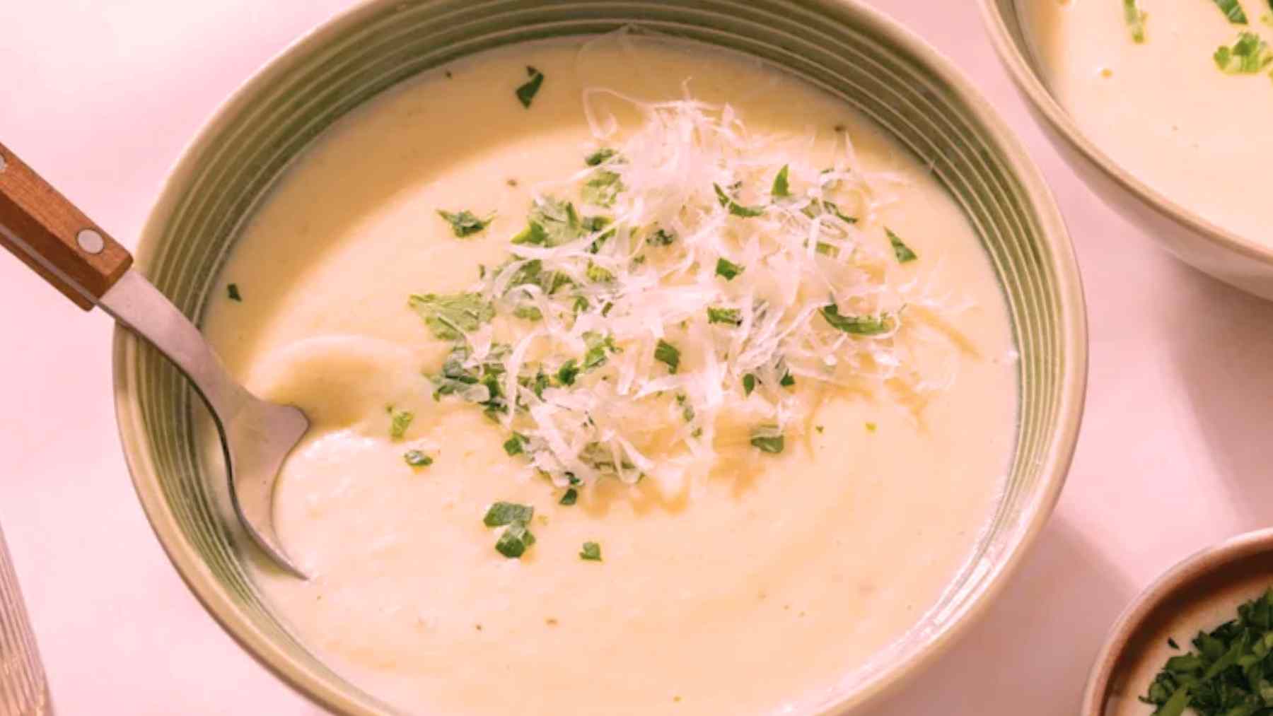 Creamy potato soup made with canned potatoes, topped with parmesan and parsley in a green bowl