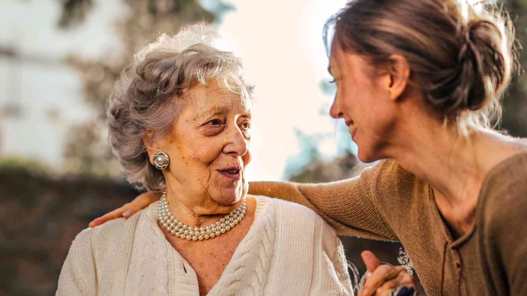 Older mother talking with adult daughter outdoors, reflecting empty nest syndrome and the quiet grief of feeling loved but less needed.