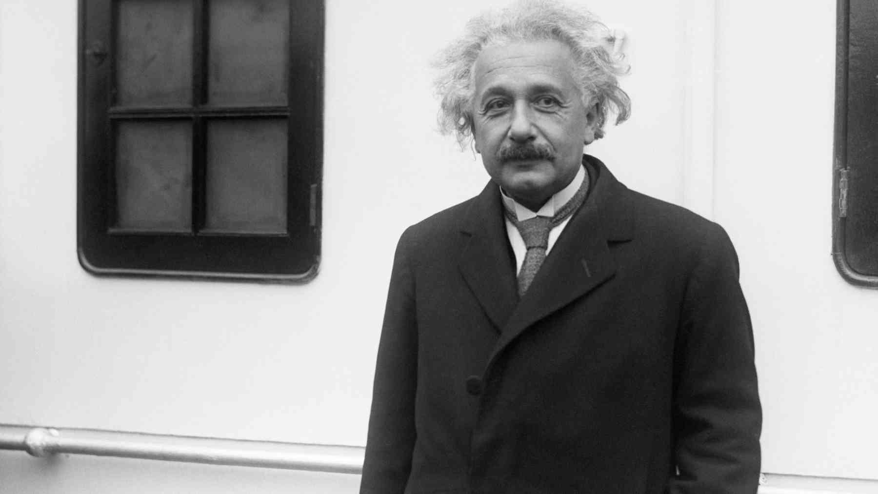 Albert Einstein standing outdoors in a dark coat during the early 20th century