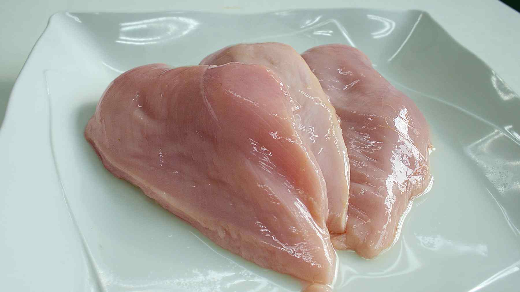 Raw chicken breasts on a plate before cooking with apple cider vinegar
