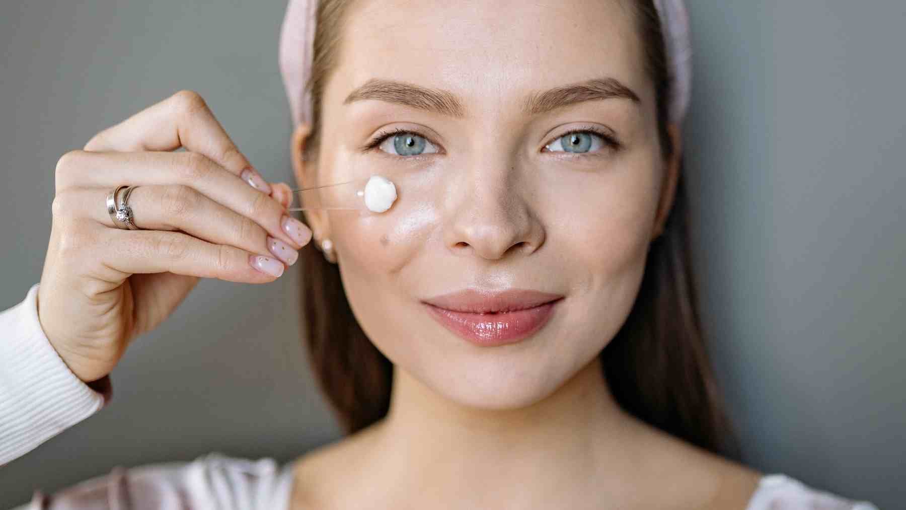 Woman applying face cream on cheek illustrating anti-aging skincare and diet-related skin aging