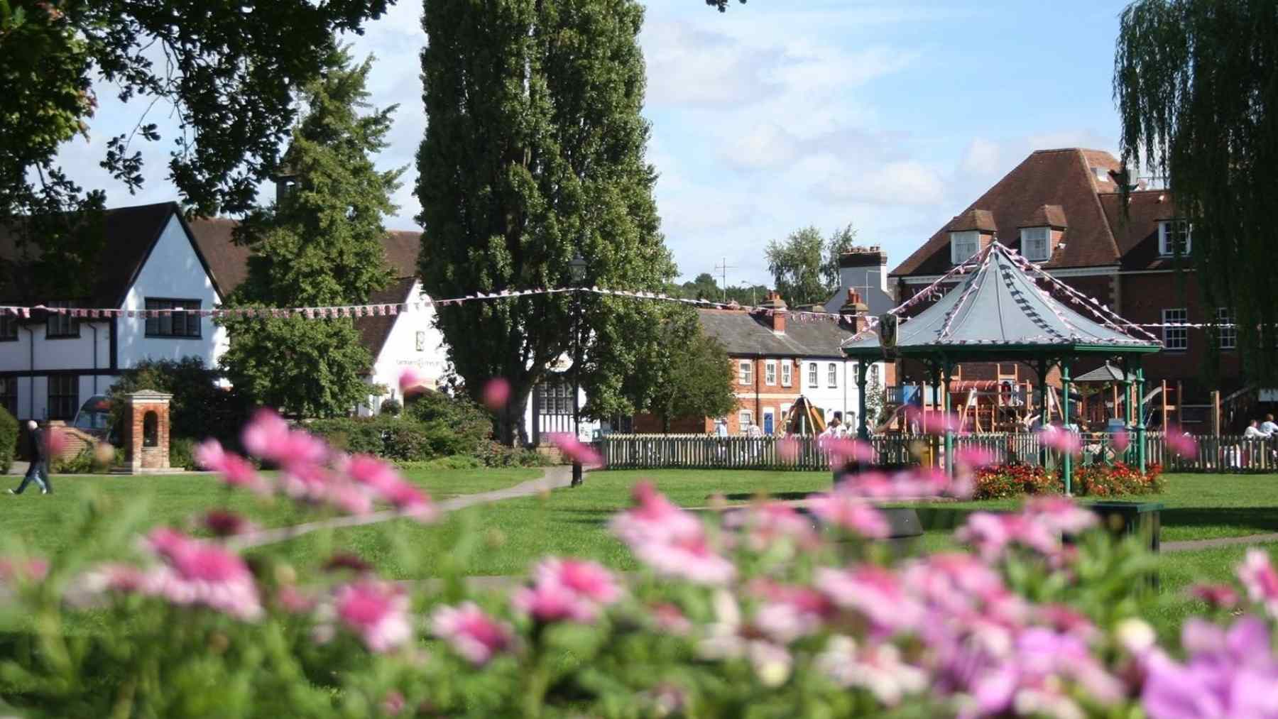 Farnham park with flowers, trees, homes, and a playground in the Surrey market town near London