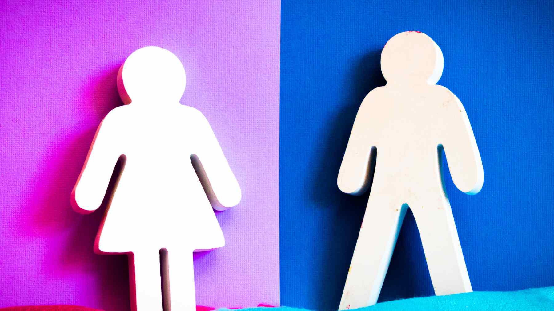 Female and male paper figures on a split pink and blue background, illustrating gender differences in emotional perception