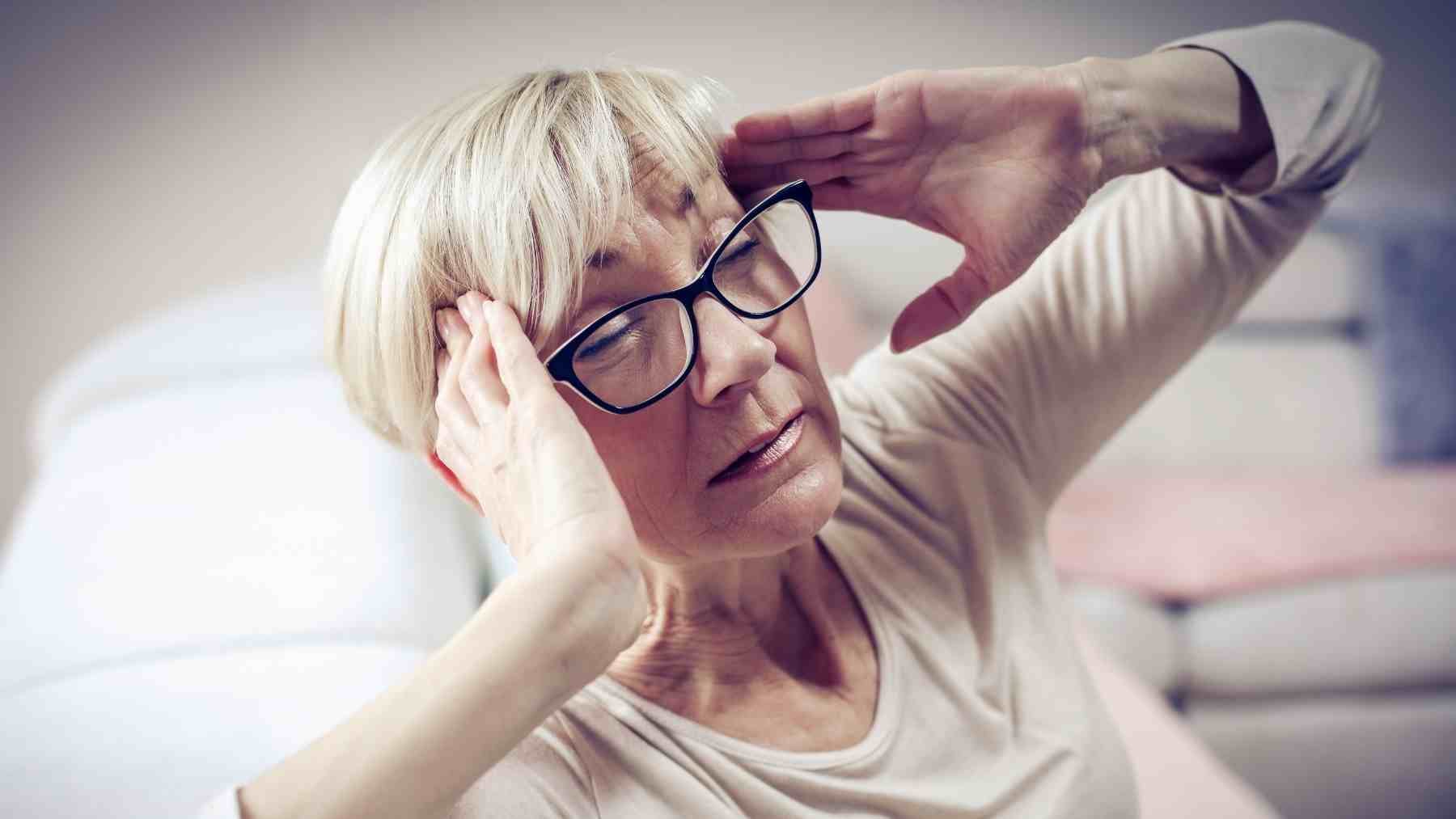 Woman holding her head during a severe migraine attack, illustrating that migraines are more than just headaches