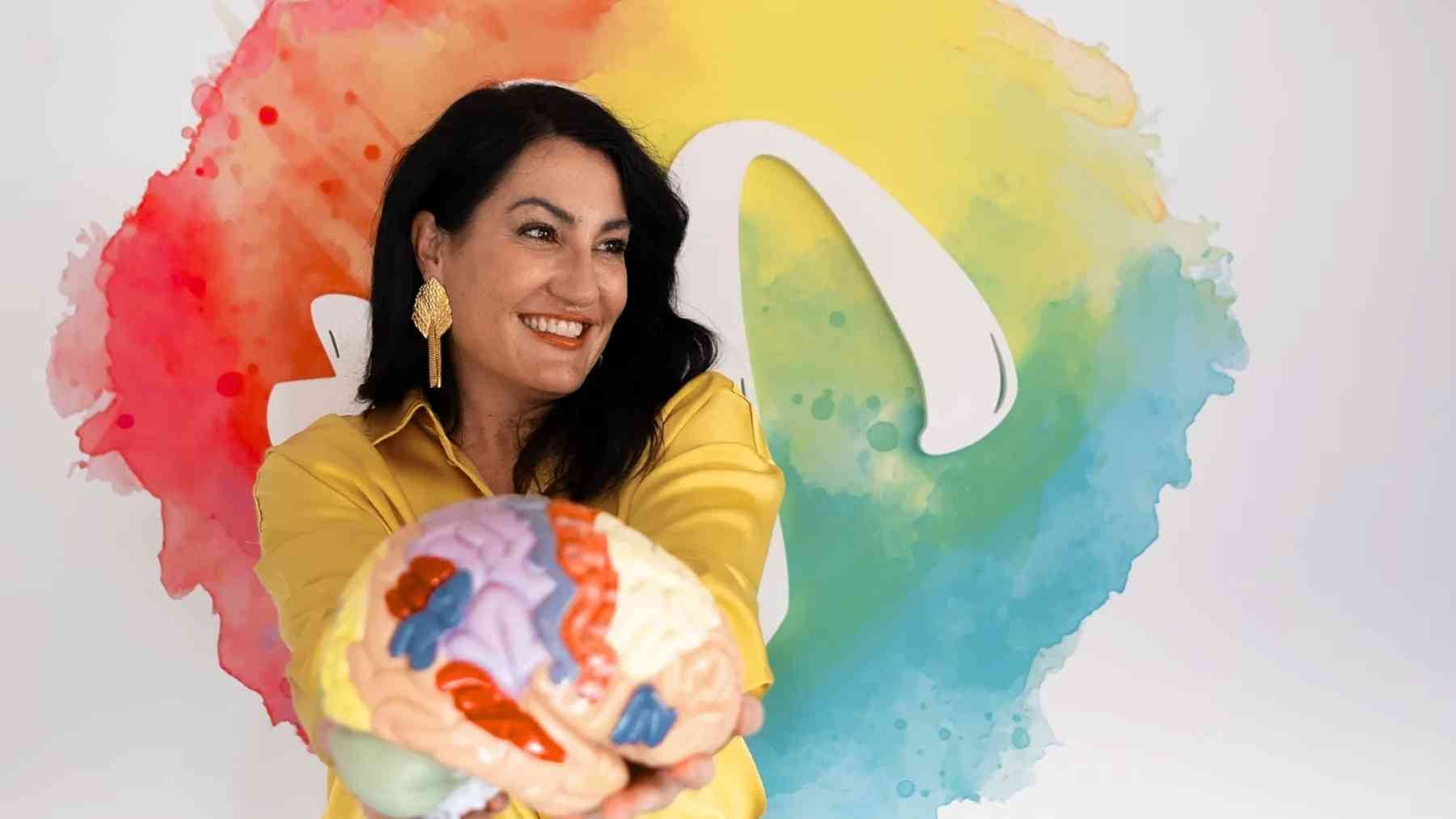 Neuroscientist holding a brain model while explaining how loneliness can affect the brain, heart, and life expectancy