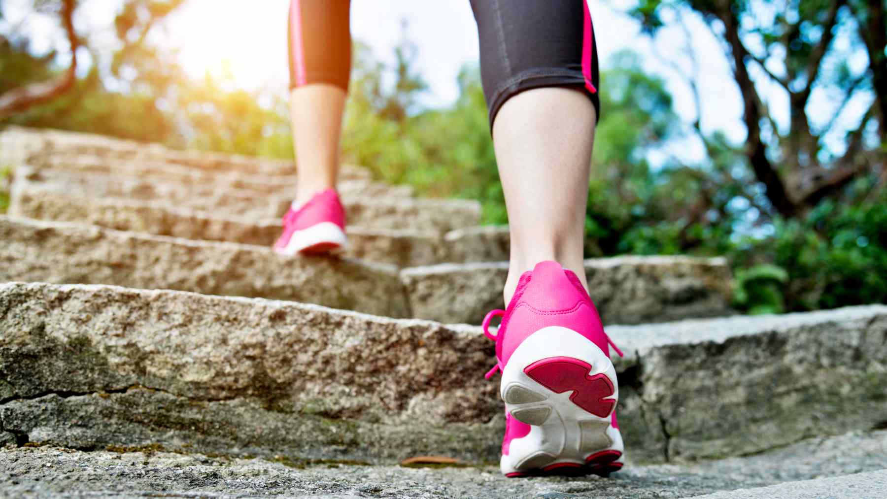 Person walking up outdoor stone steps in running shoes, illustrating the daily step counts linked to better Alzheimer’s protection.