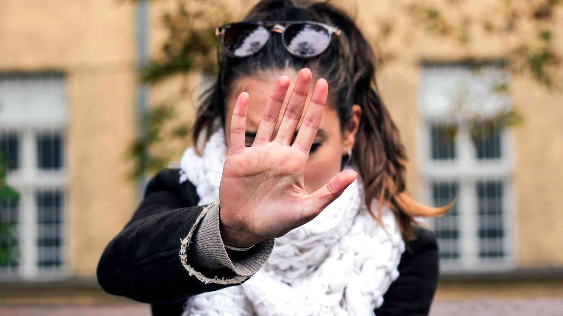 Woman raises her hand in a stop gesture while dealing with a manipulative person