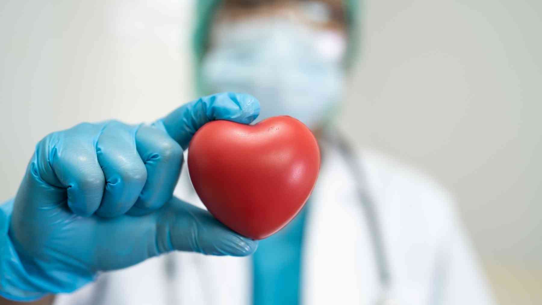 Doctor holding a red heart while explaining how swimming can improve heart health after age 40