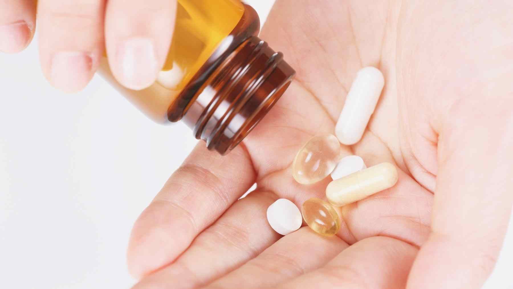 Vitamin B12 supplements being poured into a person’s hand from a brown bottle
