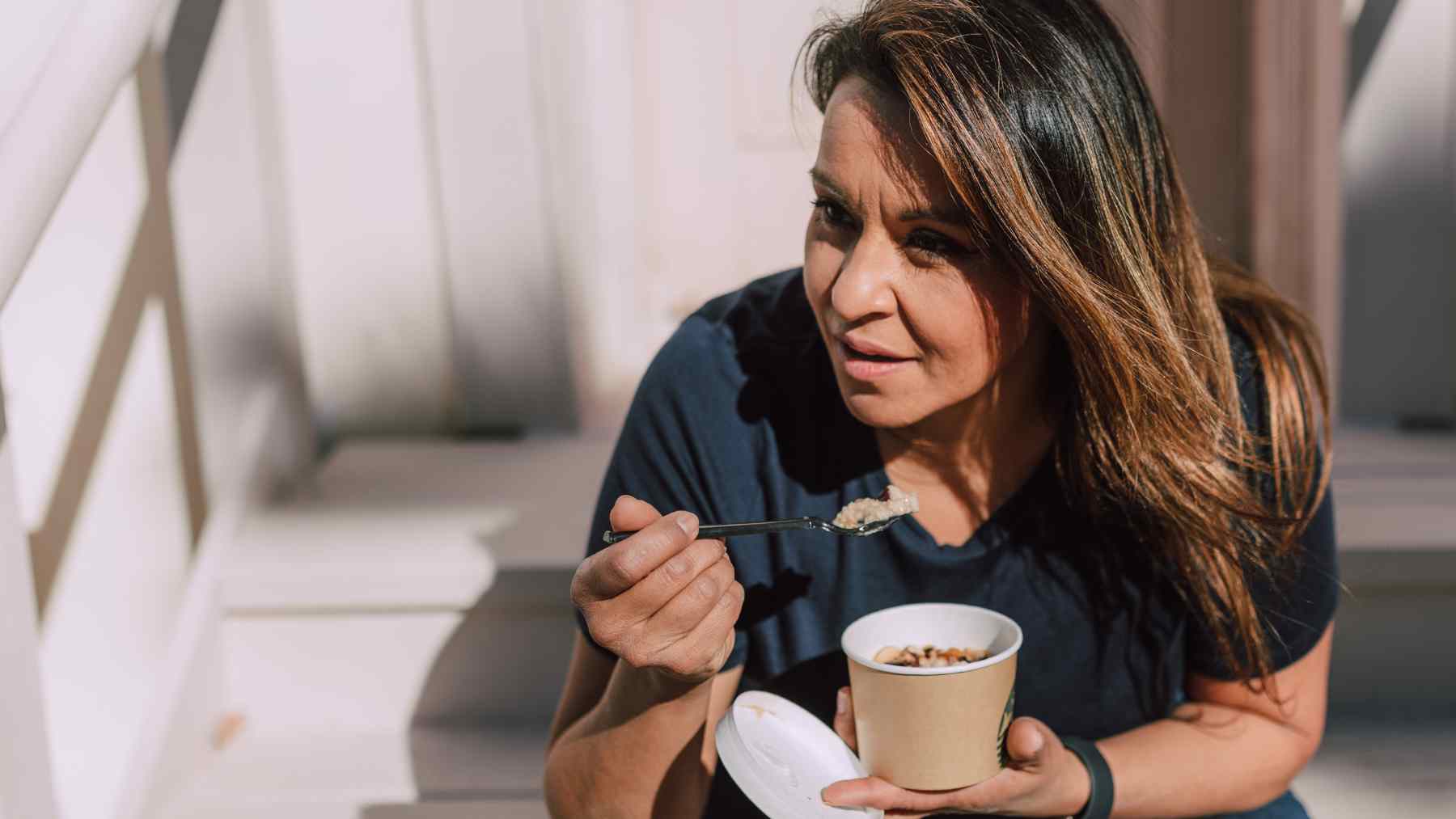 Woman eating oatmeal for breakfast, a simple morning habit linked to slower digestion and feeling fuller longer