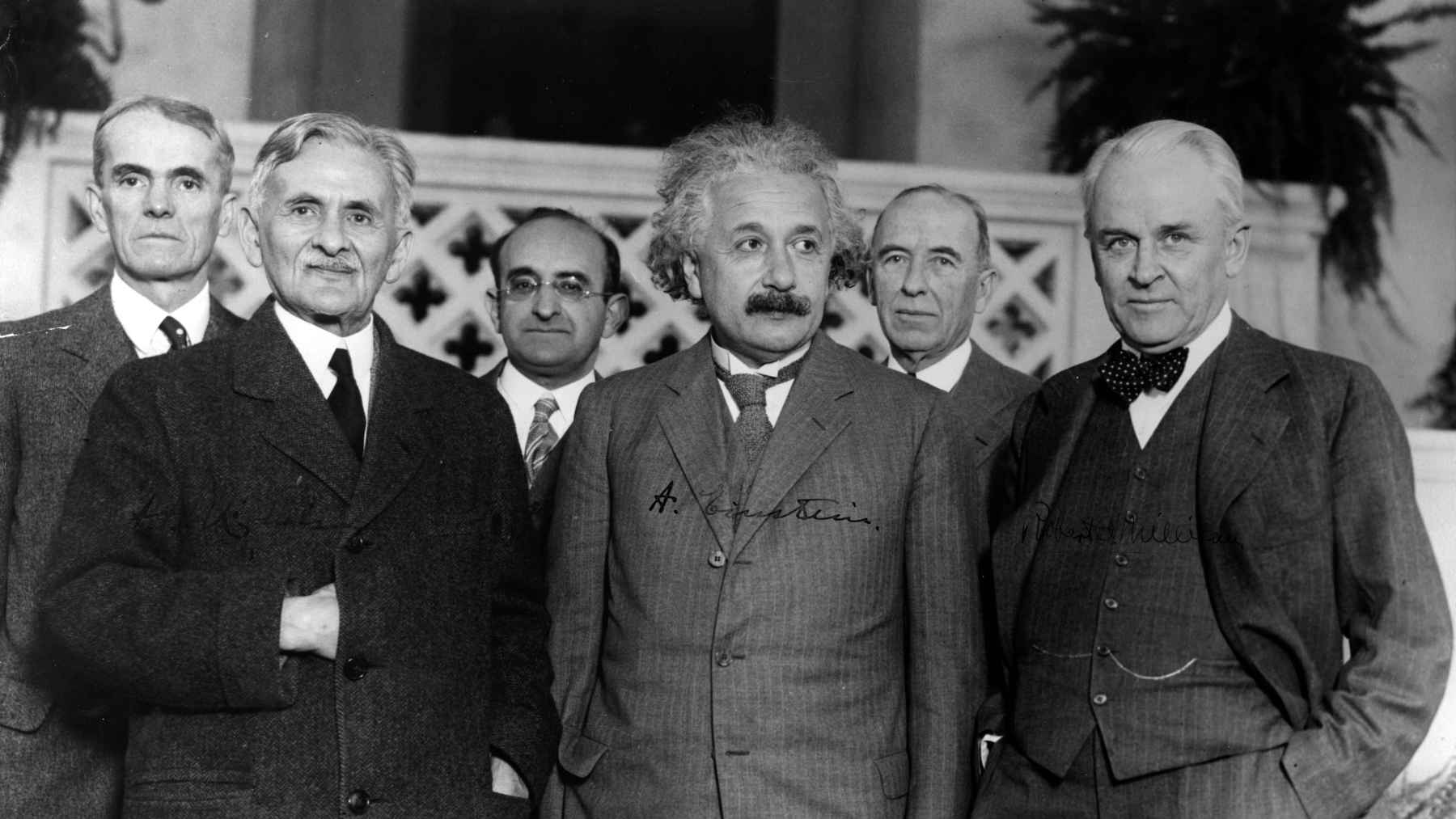 Albert Einstein standing with fellow scientists during a historic gathering, reflecting his legacy in science and human values