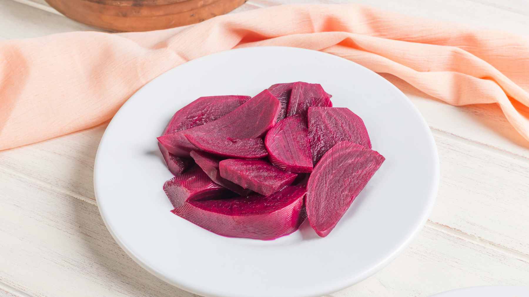 A whole roasted beet being gently peeled with a knife to reveal a vibrant, nutrient-dense interior.