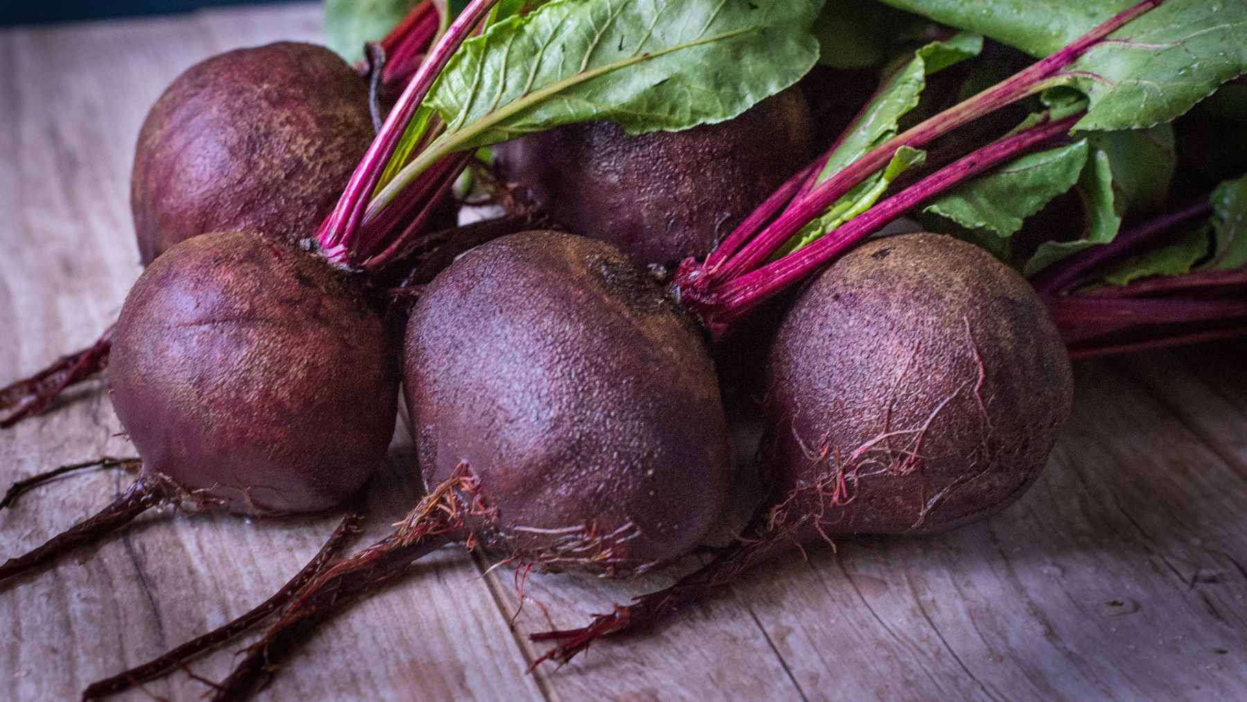 A whole roasted beet being gently peeled with a knife to reveal a vibrant, nutrient-dense interior.