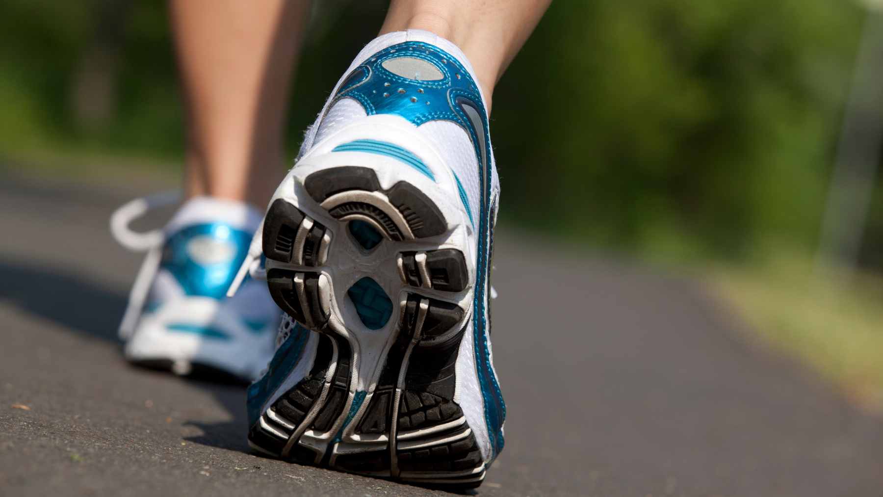 A person walking briskly on a sunny park path, maintaining a steady pace to maximize aerobic fitness benefits.