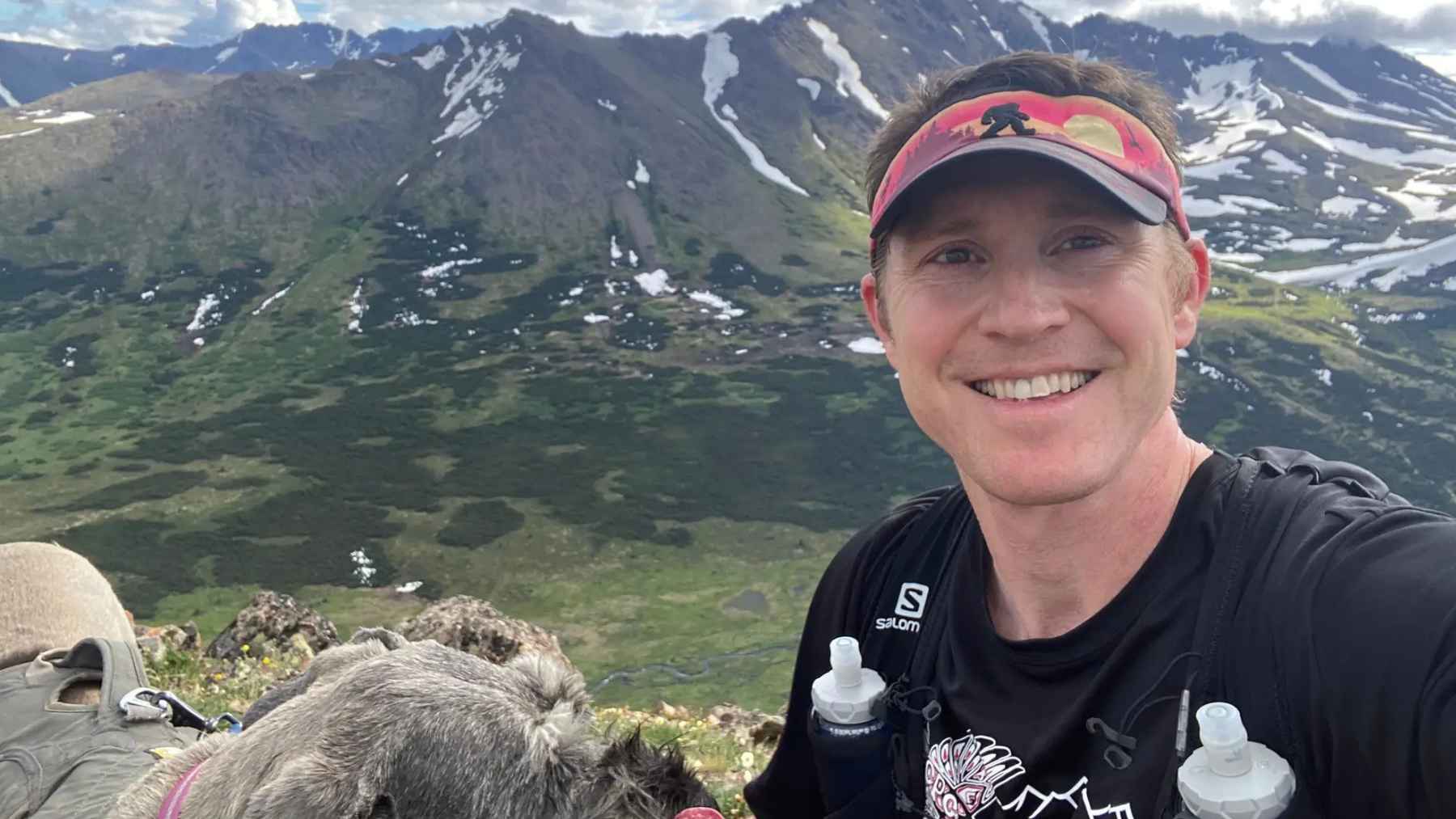 Cardiologist Jake Kelly hiking with his dog in the Alaska mountains, reflecting the active lifestyle habits he recommends for heart health